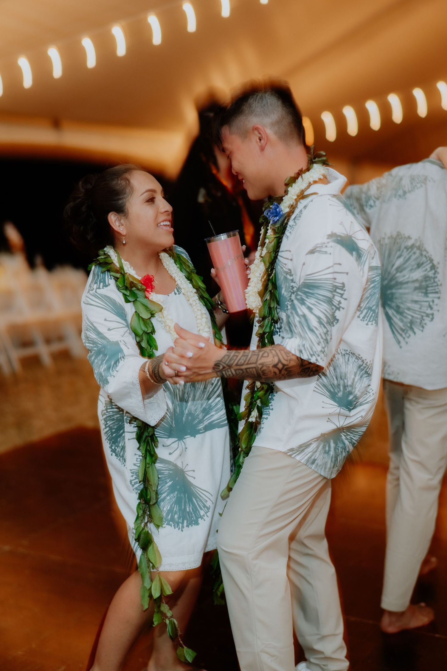 Couple in matching tropical print outfits dancing at their Hawaiian-themed reception.
