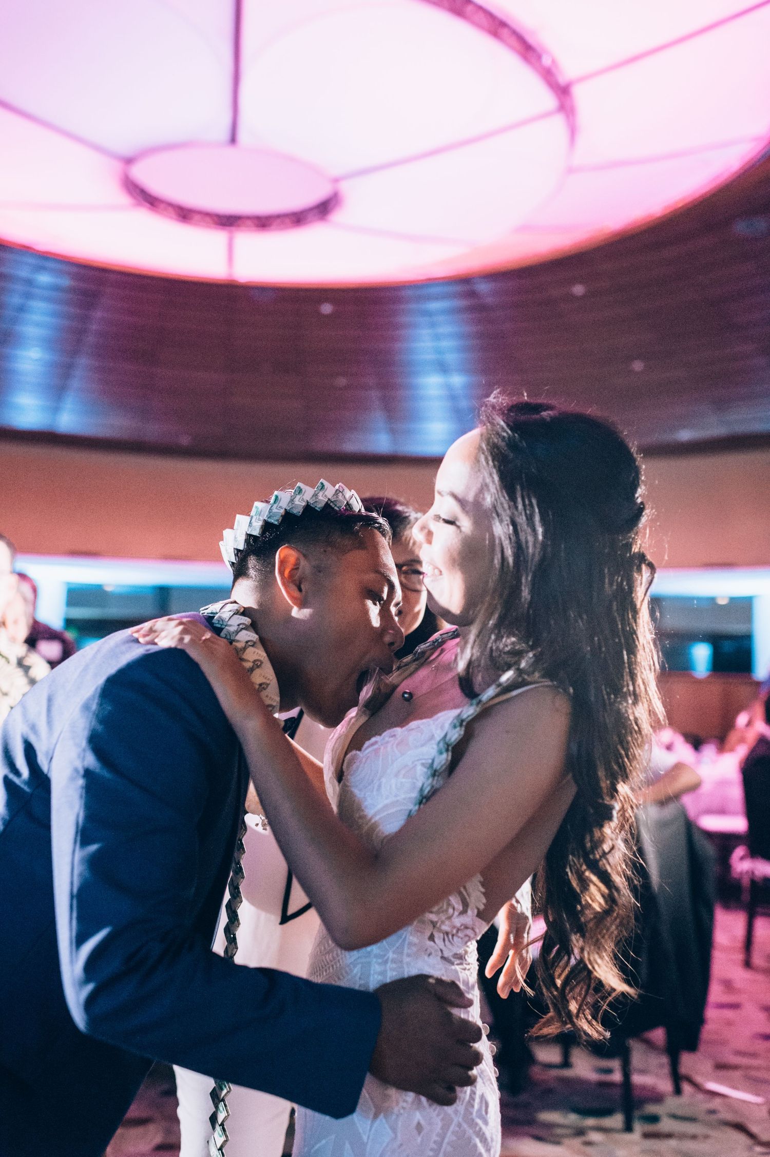 Romantic dance floor moment under pink mood lighting at an indoor celebration.