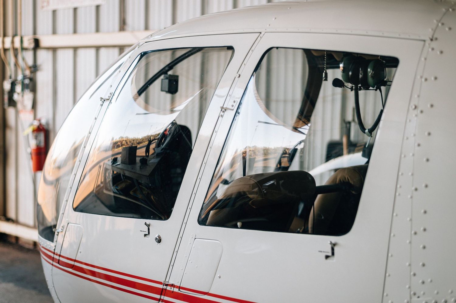 Side view of white aircraft with red trim parked in indoor hangar space.