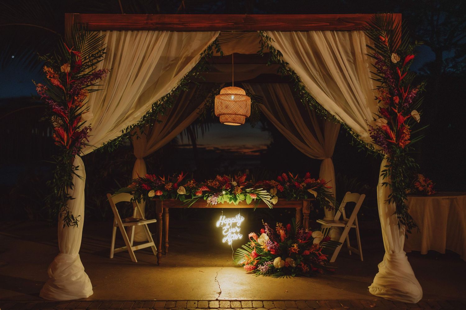 Evening wedding reception setup with draped fabric and hanging lights creating ambient atmosphere.