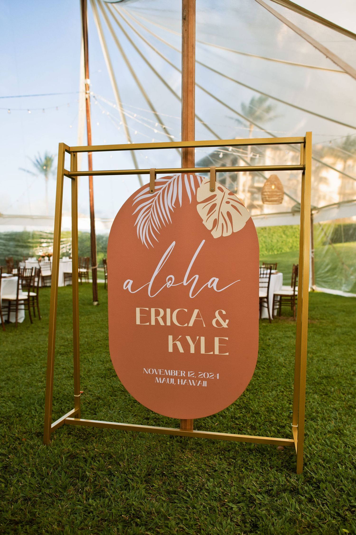 Terracotta aloha wedding welcome sign for Erica and Kyle, November 2024, Maui Hawaii, displayed on gold stand outdoors.
