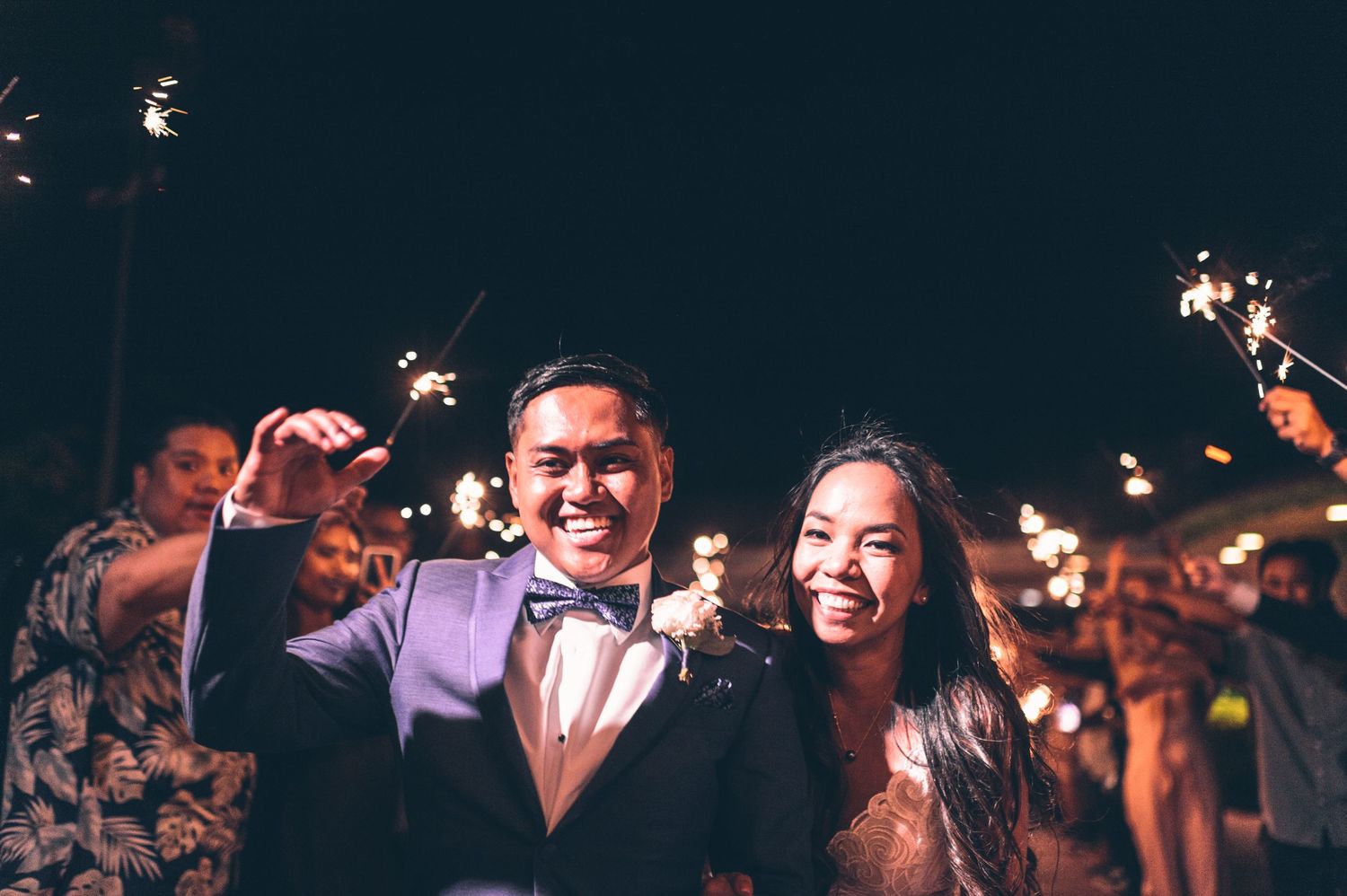 Silhouettes of wedding guests dancing and celebrating in a dark venue with dramatic lighting.