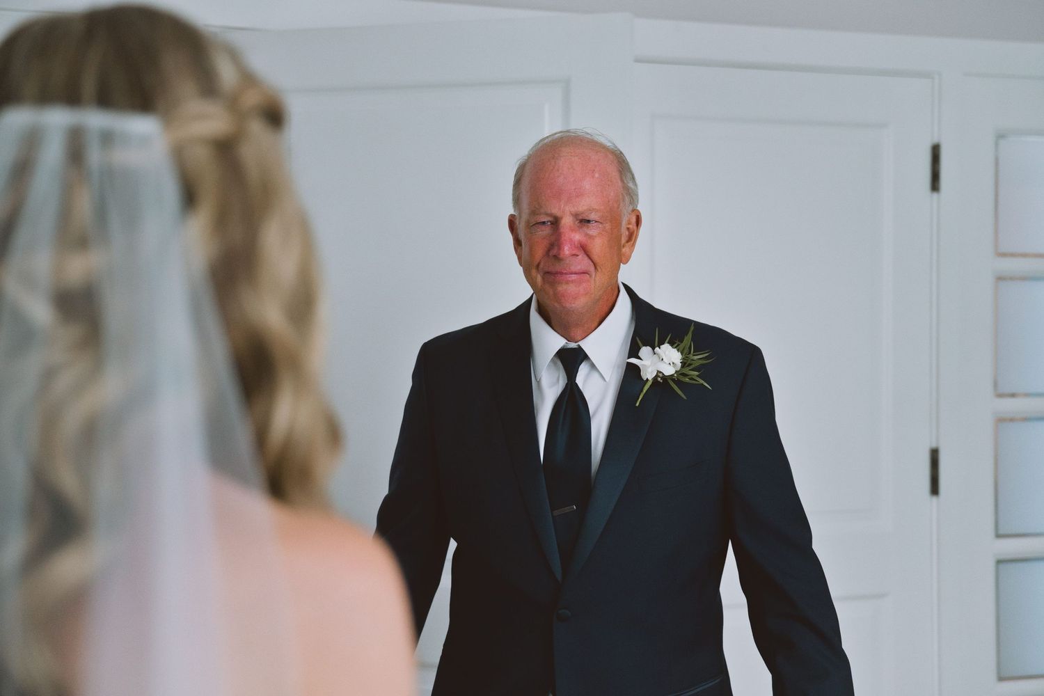 Father seeing his daughter in her wedding dress for the first time, emotional first look moment at a wedding.