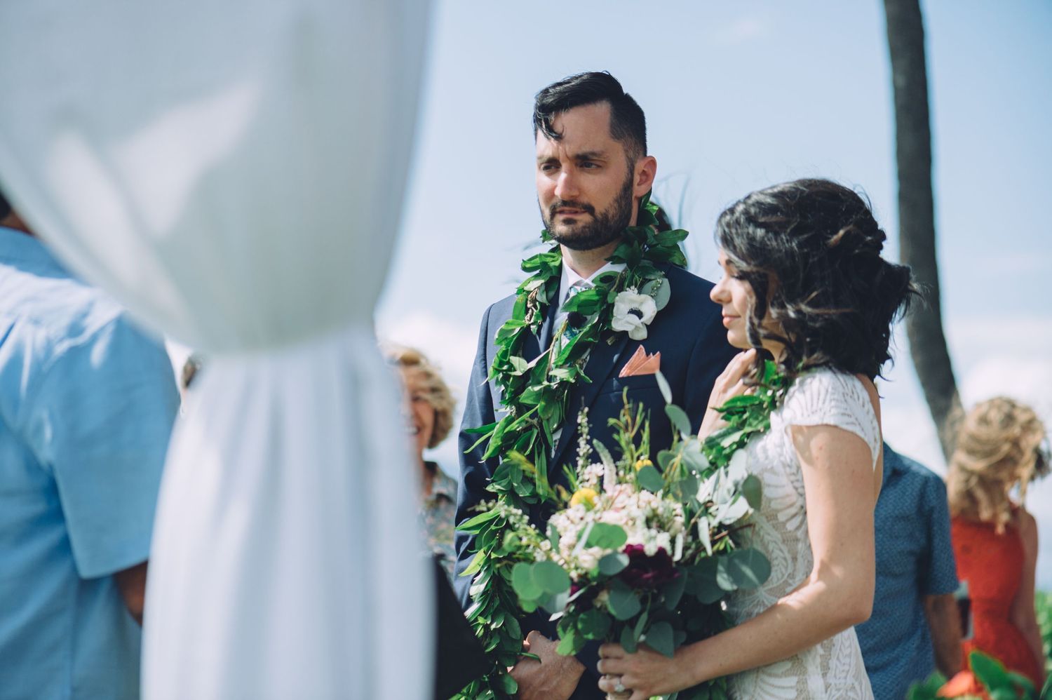 Wedding celebration with guests mingling outdoors under palm trees.