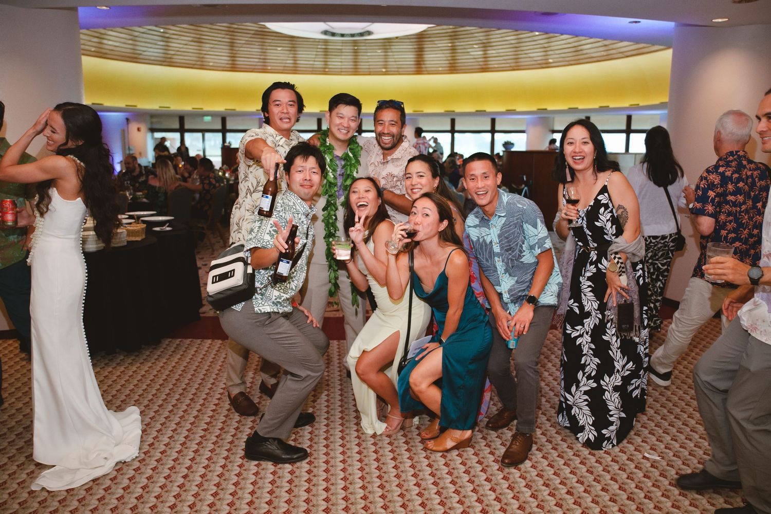 Group of friends posing and dancing together at a festive indoor wedding reception party.