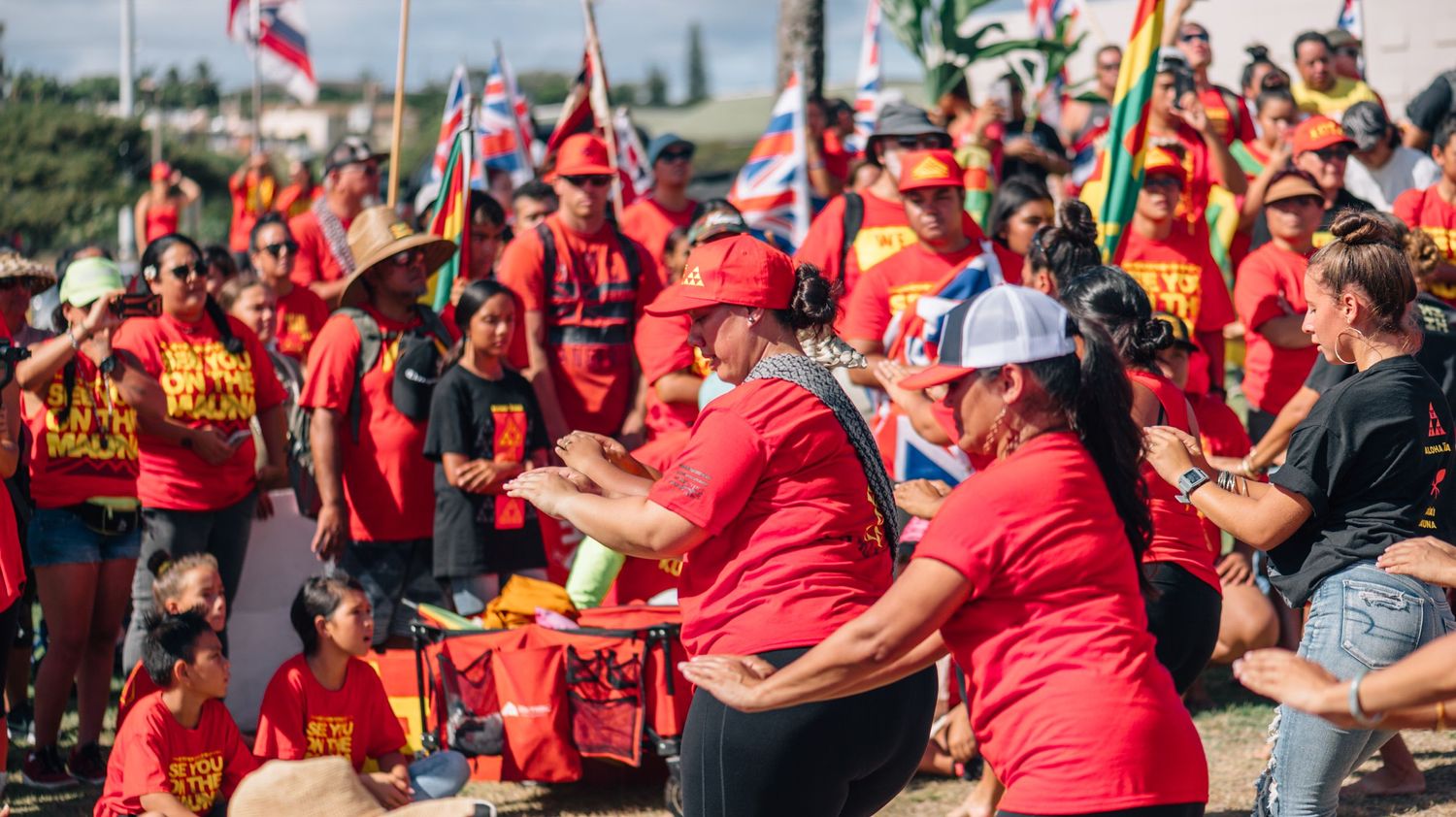 Crowd dressed in red shirts gathers outdoors for a community event.