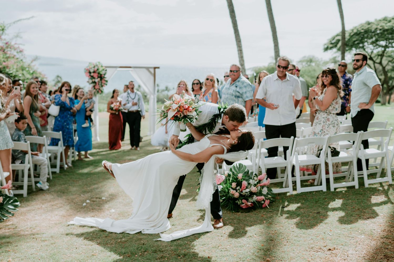 Wedding guests celebrate during an outdoor ceremony with ocean views.