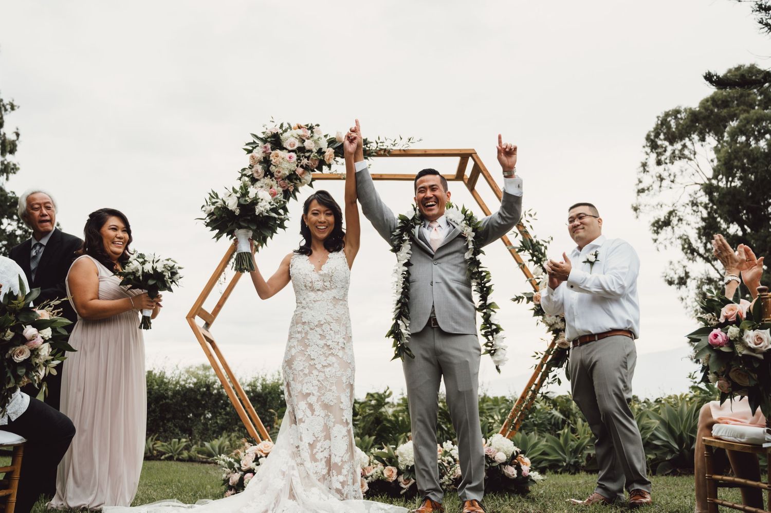 Outdoor wedding ceremony with wooden hexagon arch and floral decorations.