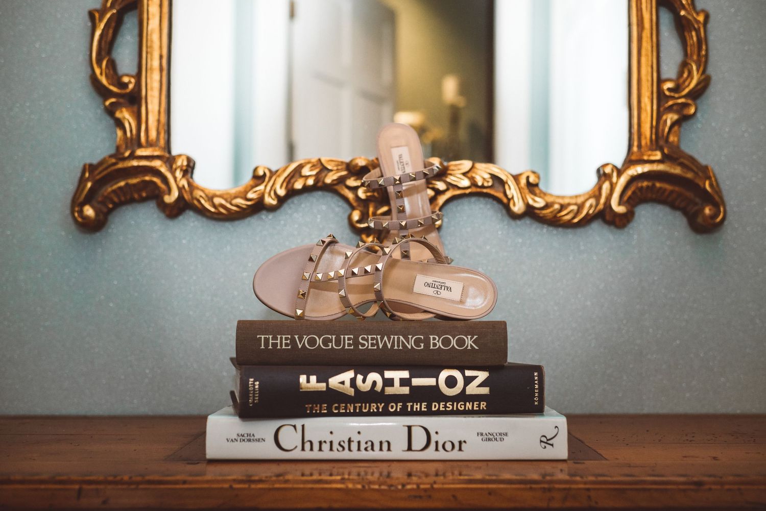 Vintage books including Vogue, Wizard of Oz, and Christian Dior displayed on shelf.