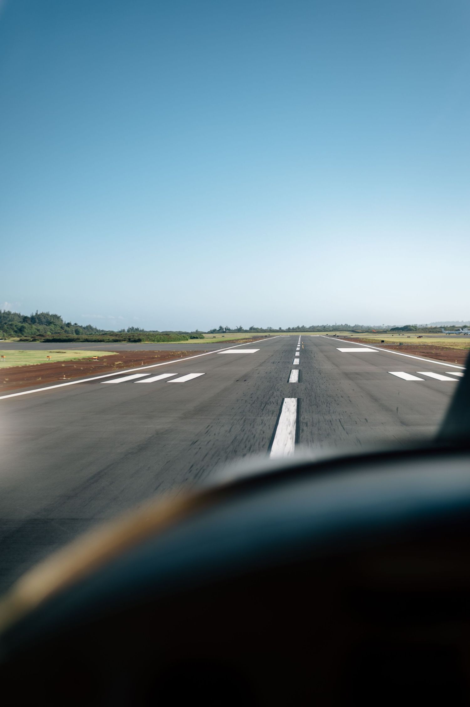 View of an airport runway from cockpit perspective on a clear day.