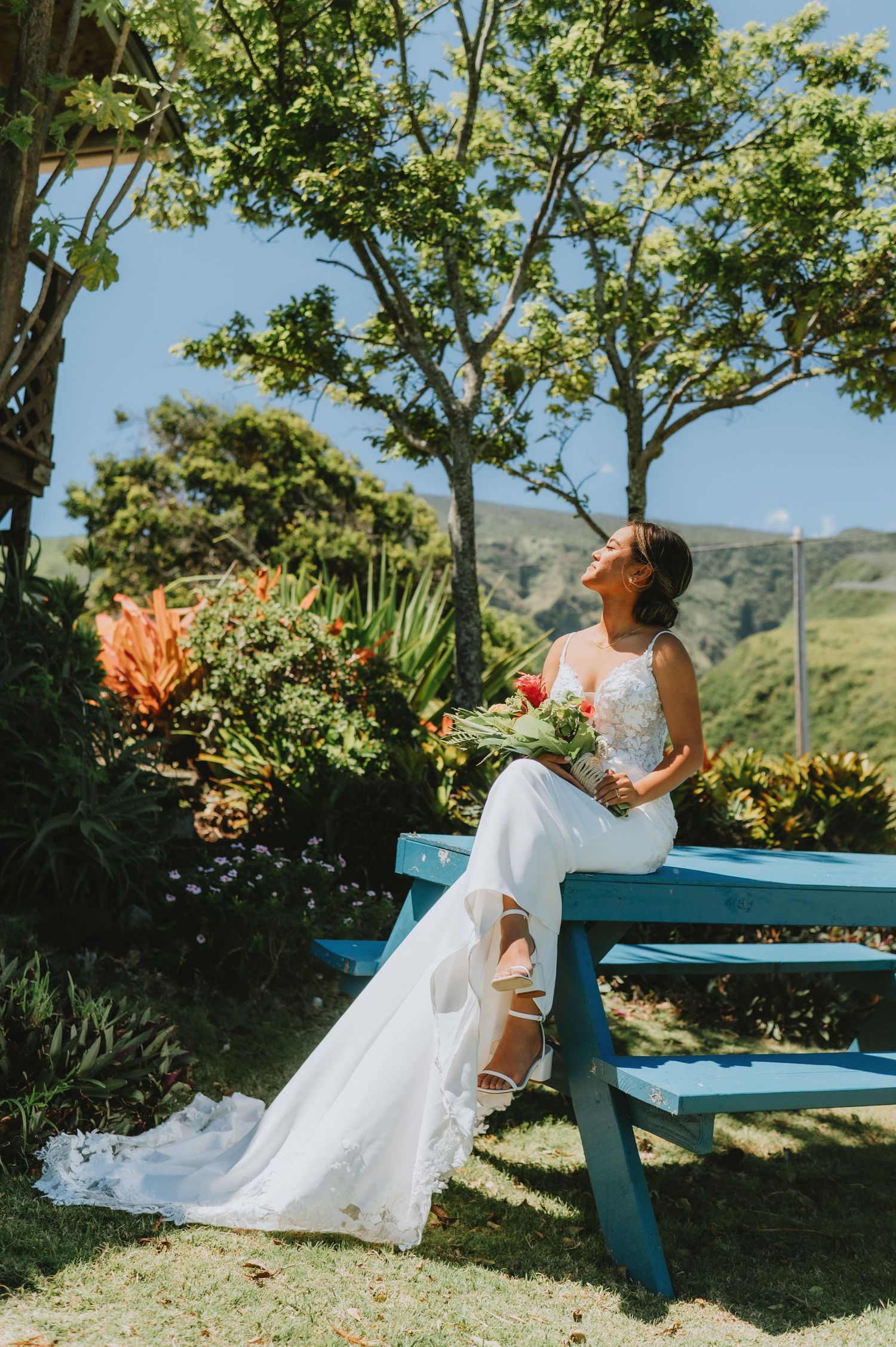 Wedding dress flowing in breeze on bright sunny day with mountain backdrop.
