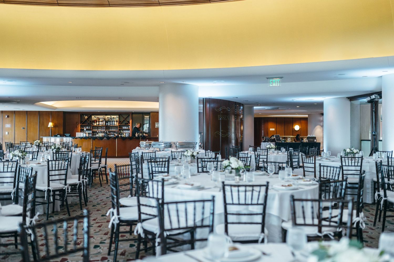 Elegant wedding reception hall setup with black chiavari chairs and white tablecloths.