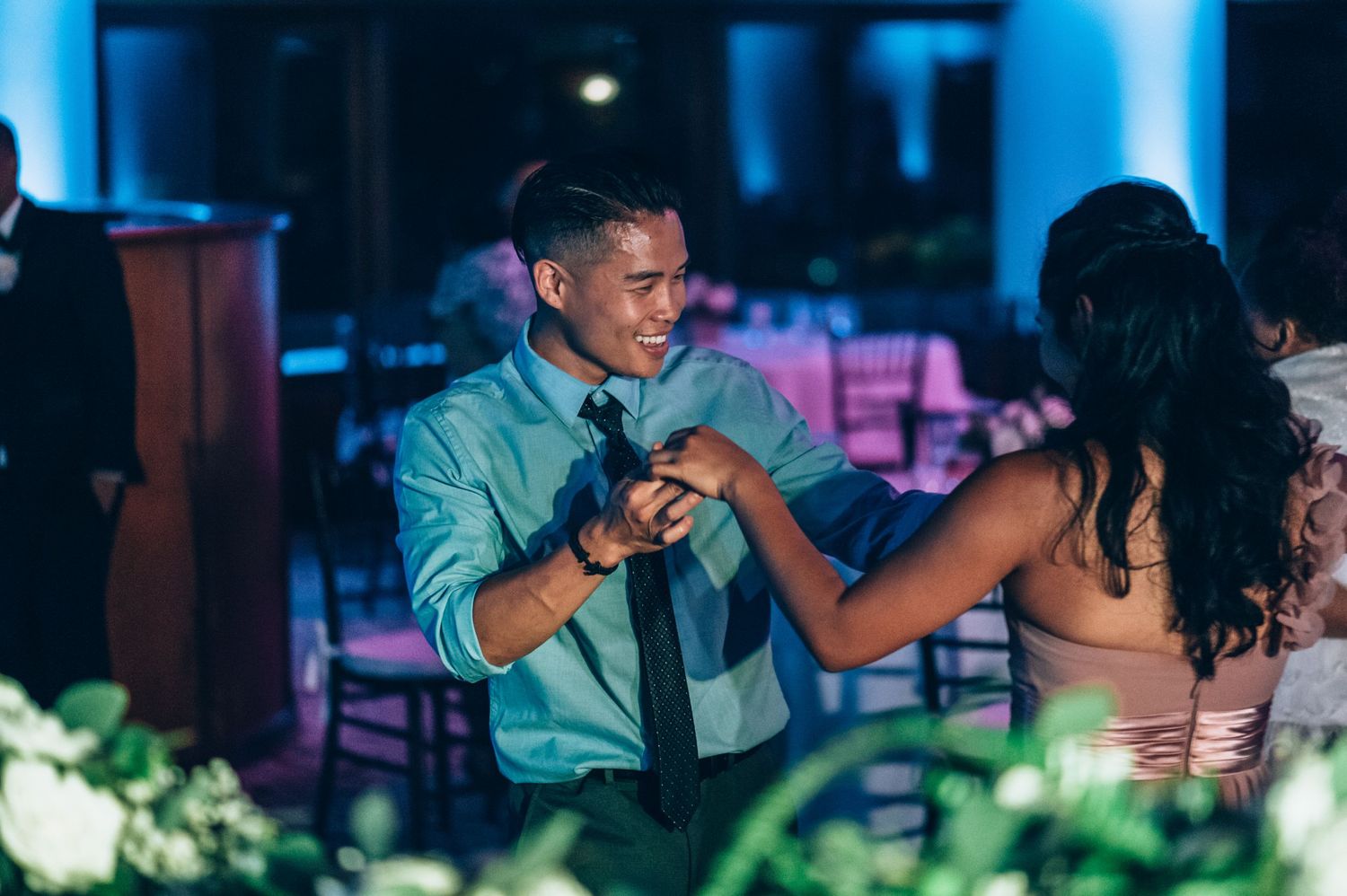 Guests enjoying food and drinks at an elegant indoor reception with blue lighting.