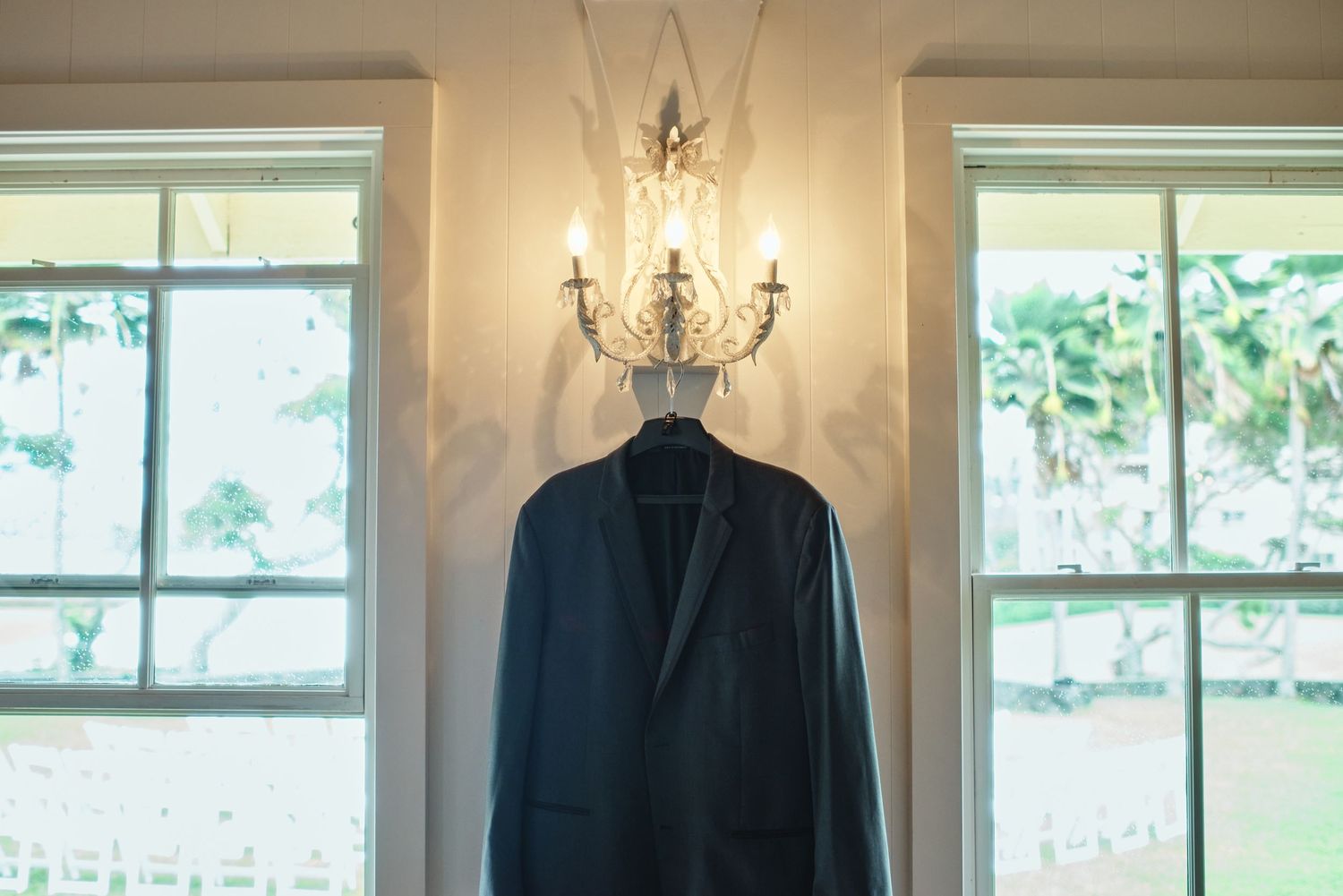 Elegant white interior room with chandelier and large windows for wedding preparations.