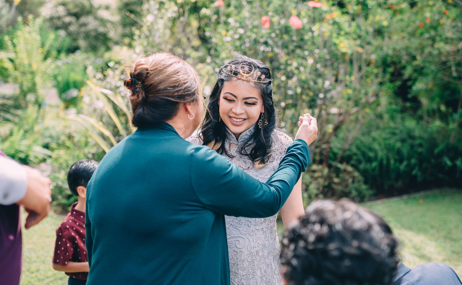 Wedding guests share warm hugs and congratulations in a garden setting.