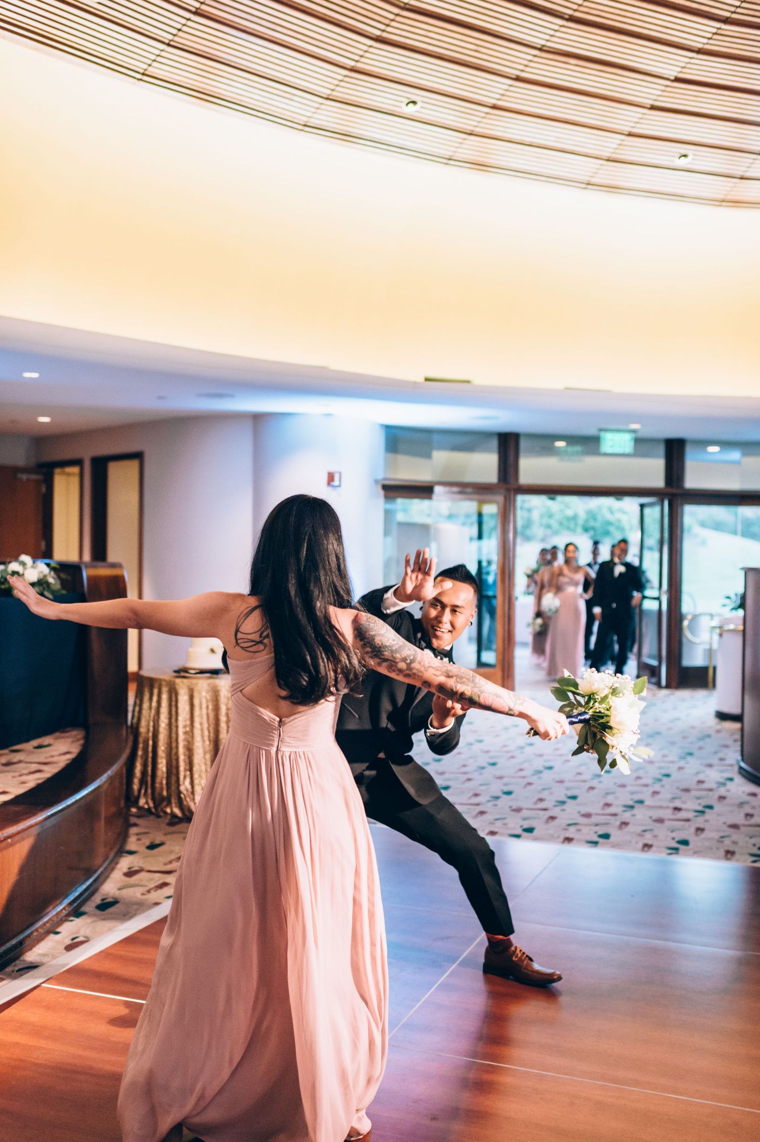 Dancers in formal attire perform a coordinated dance sequence in an elegant ballroom setting.