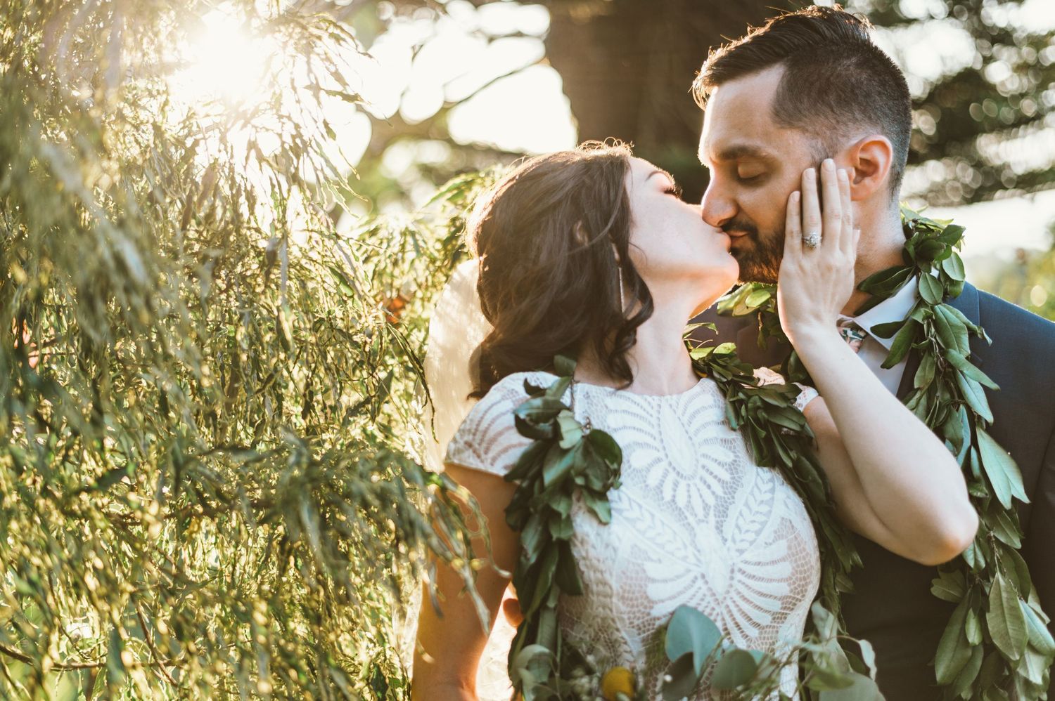 Golden hour wedding portraits with couple wearing leafy garlands in garden setting.