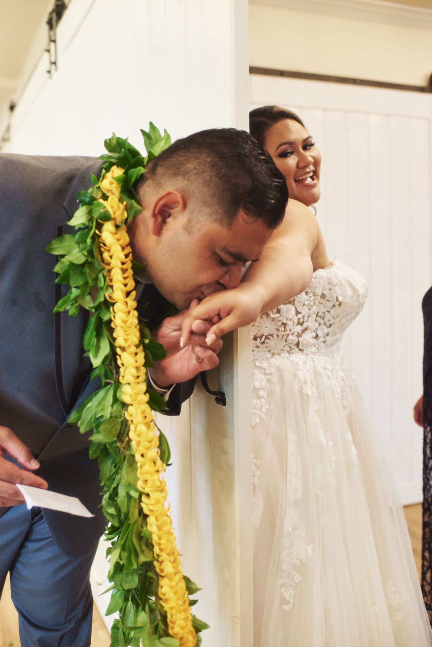 A touching moment captured during a wedding with traditional Hawaiian lei and formal attire.