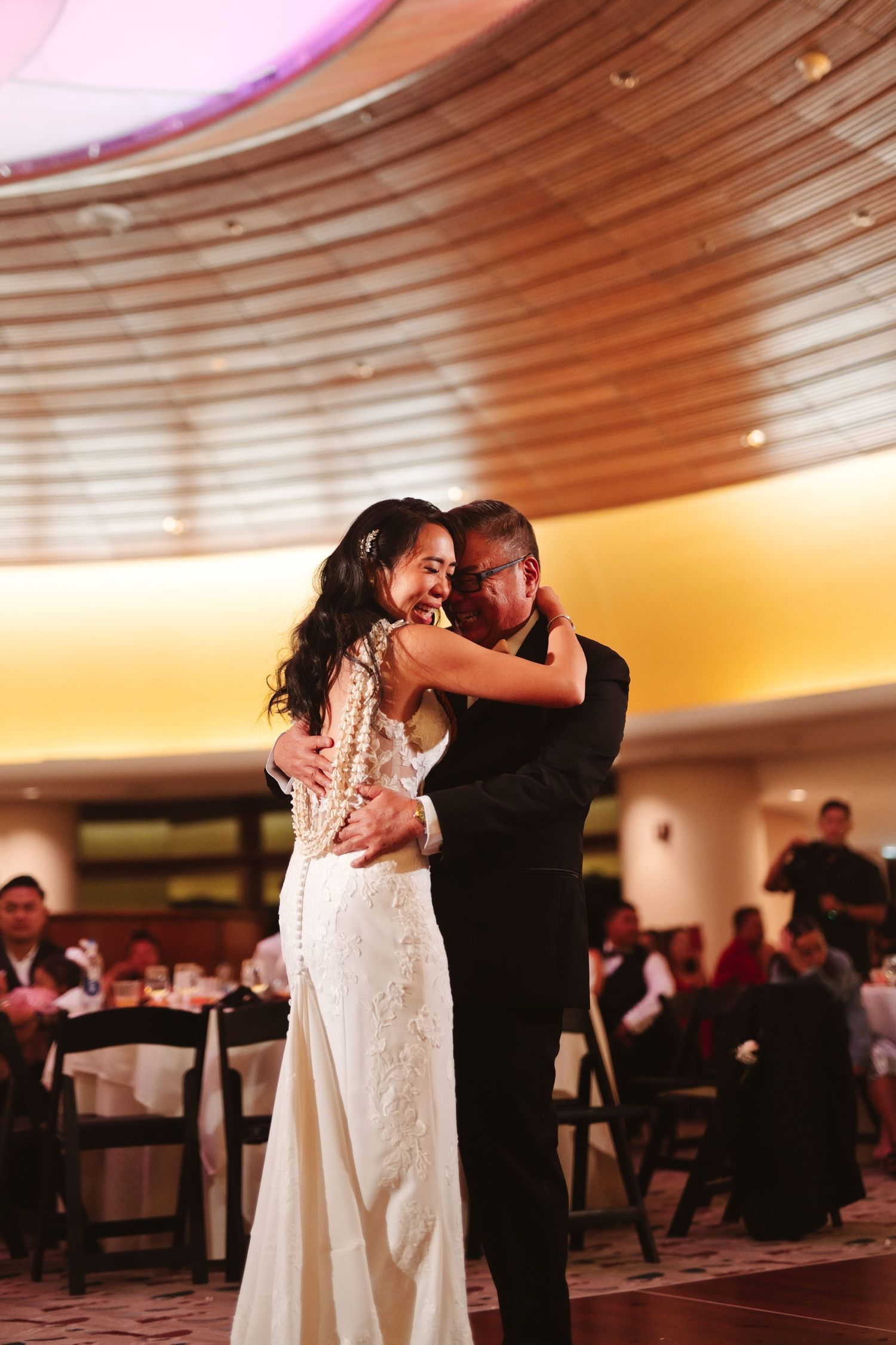 Bride and father share an emotional first dance at wedding reception in elegant ballroom venue.