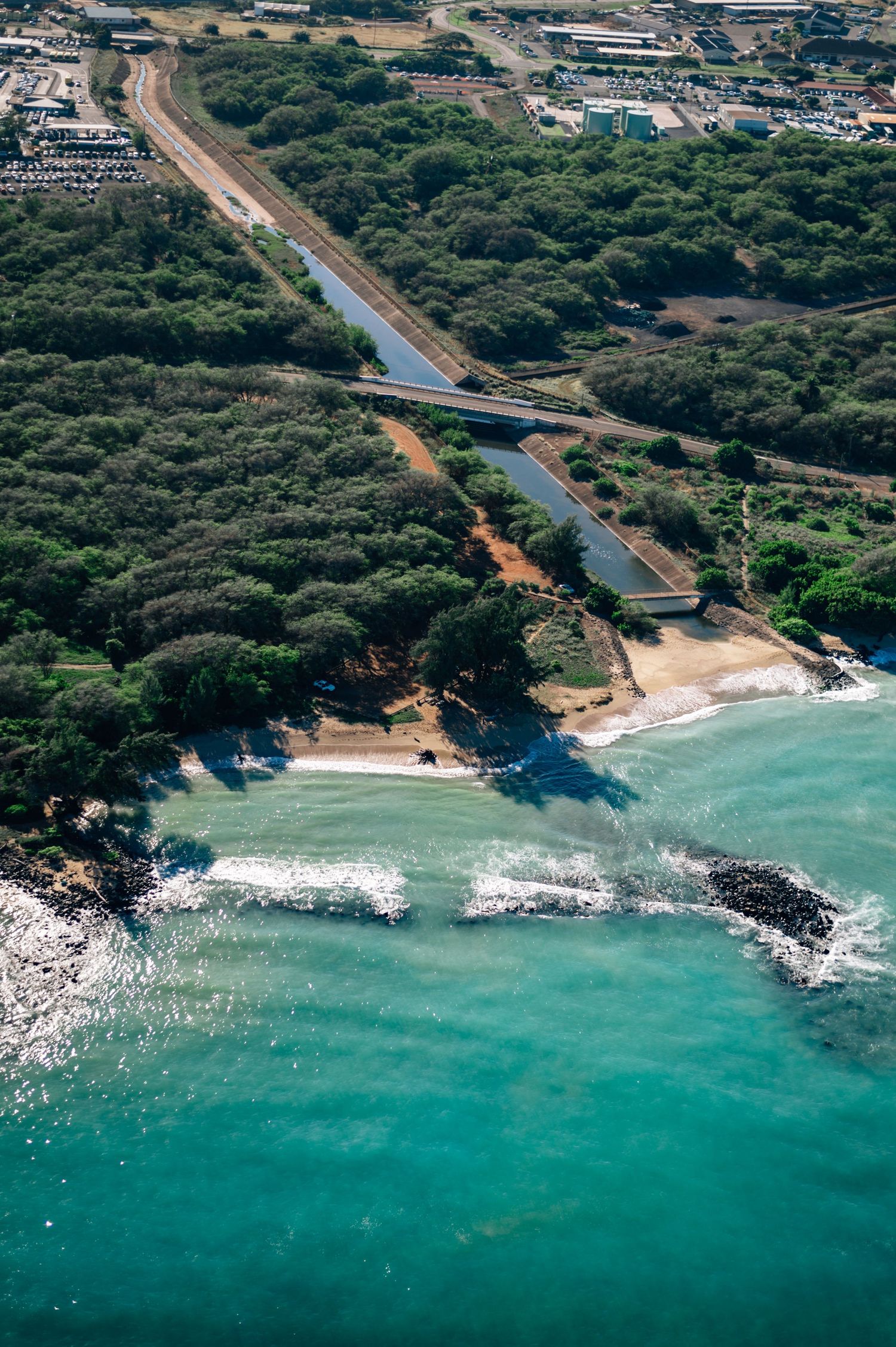 Aerial view of a coastal cove with turquoise waters meeting forested shoreline.