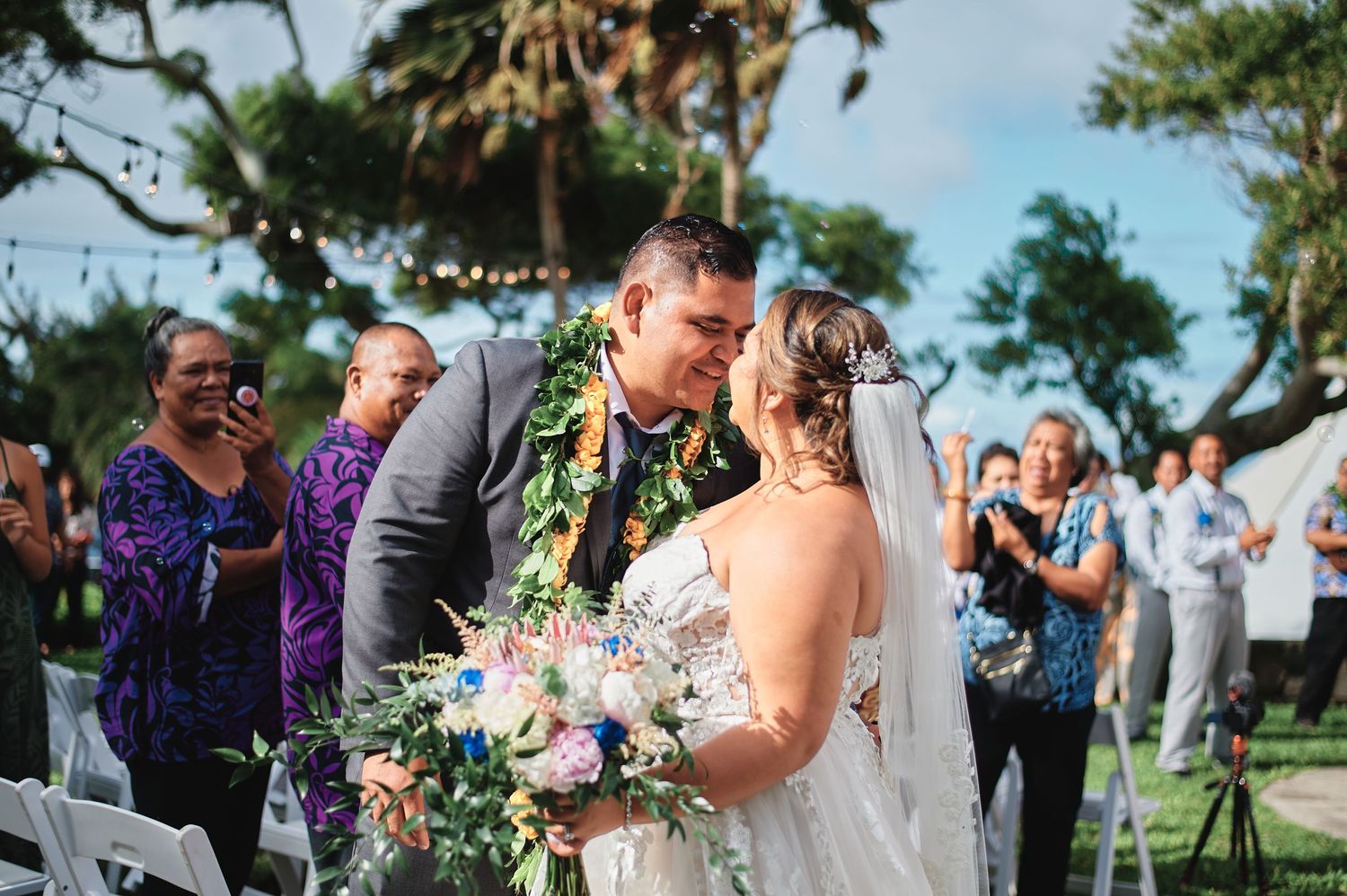 Wedding celebration takes place in scenic outdoor tropical setting.