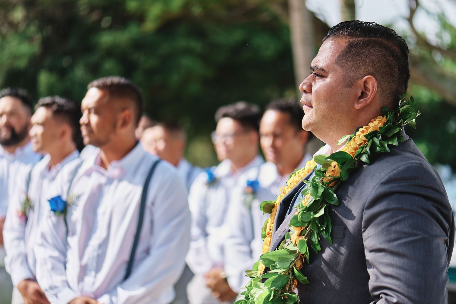 Wedding ceremony setup with guests seated outdoors under tropical trees.