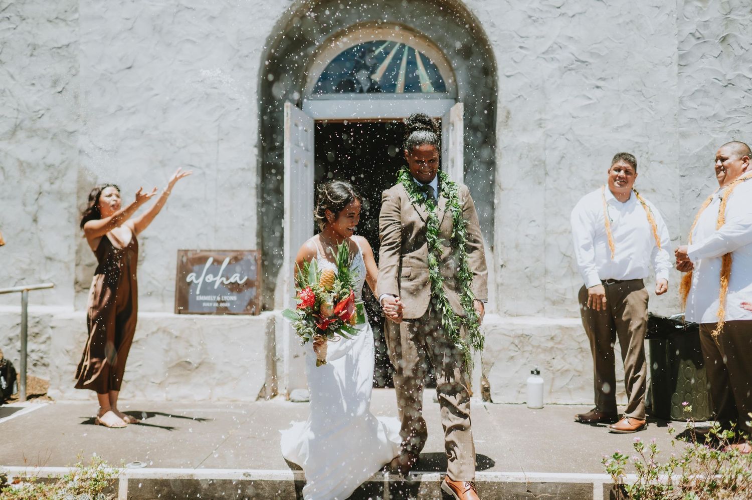 Festive wedding celebration outside historic white church with arched windows.