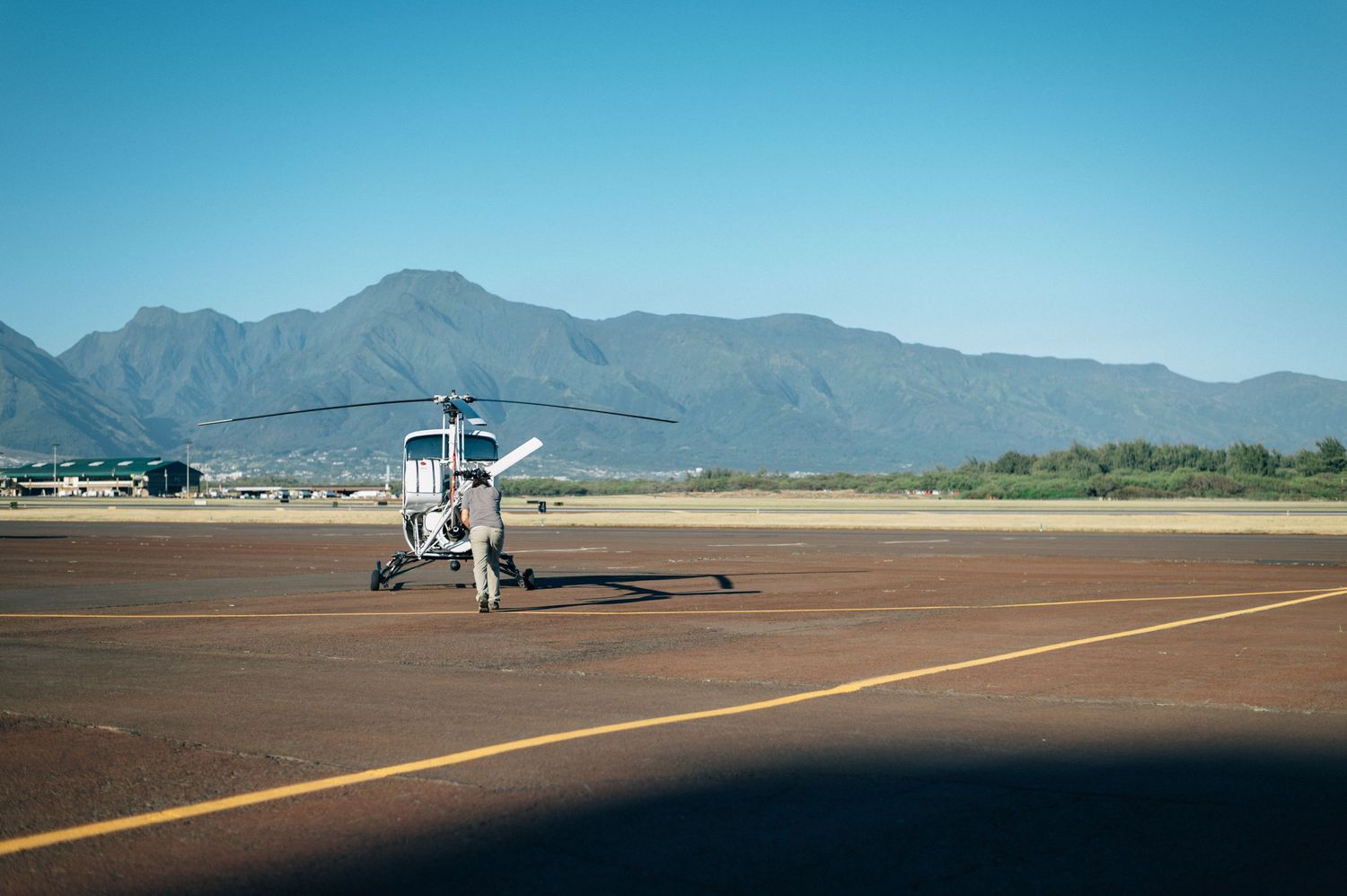 Wide panoramic view of airfield with mountains and clear blue sky.