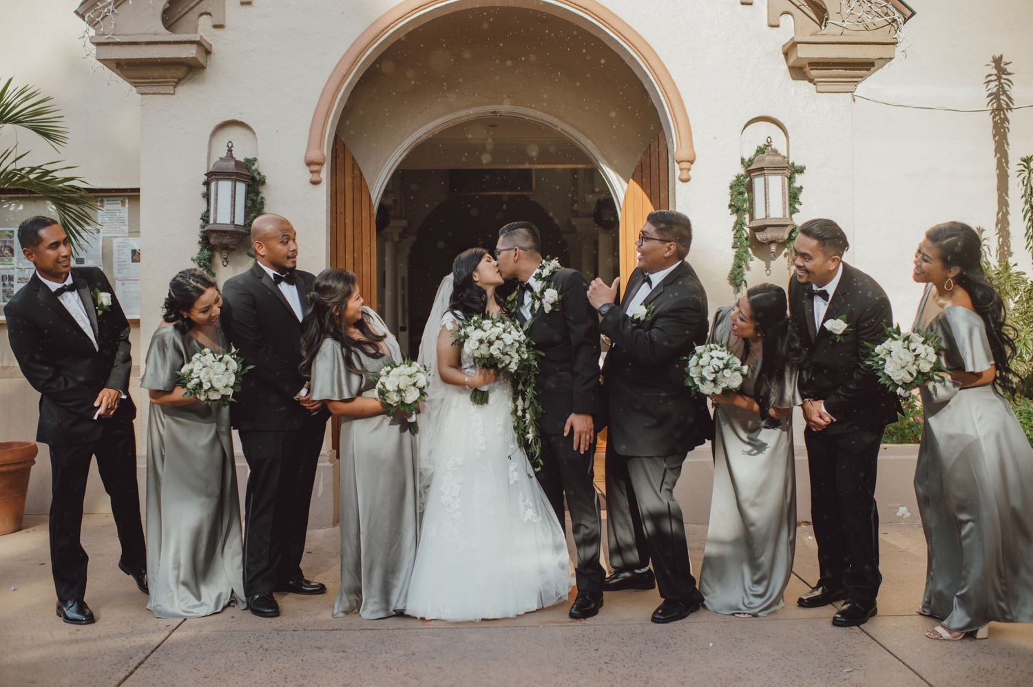 Bridal party watching with excitement as bride and groom kiss at Maria Lanakila church in Lahaina, HI