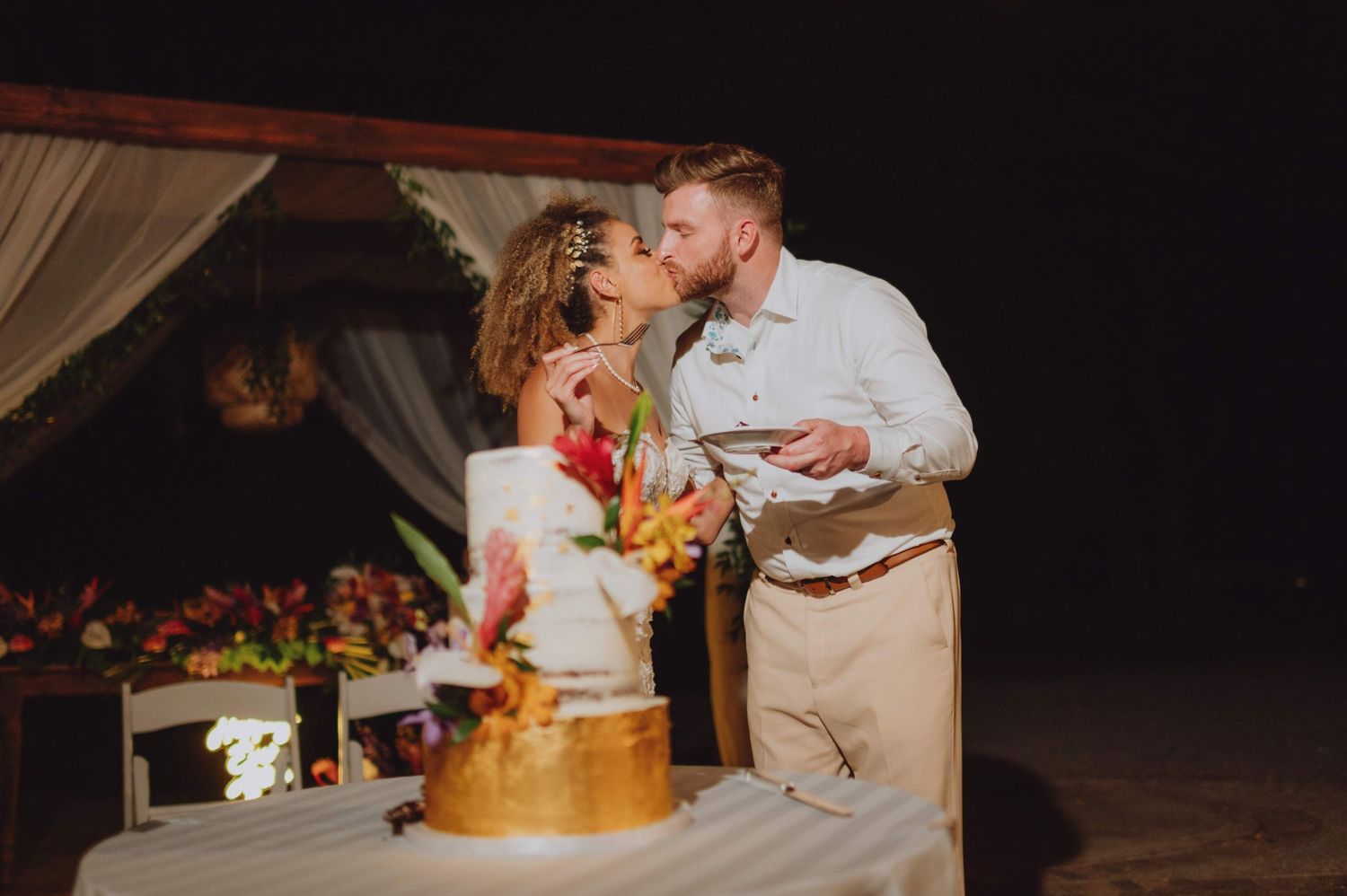 Wedding guests dance and celebrate during an evening reception under string lights.