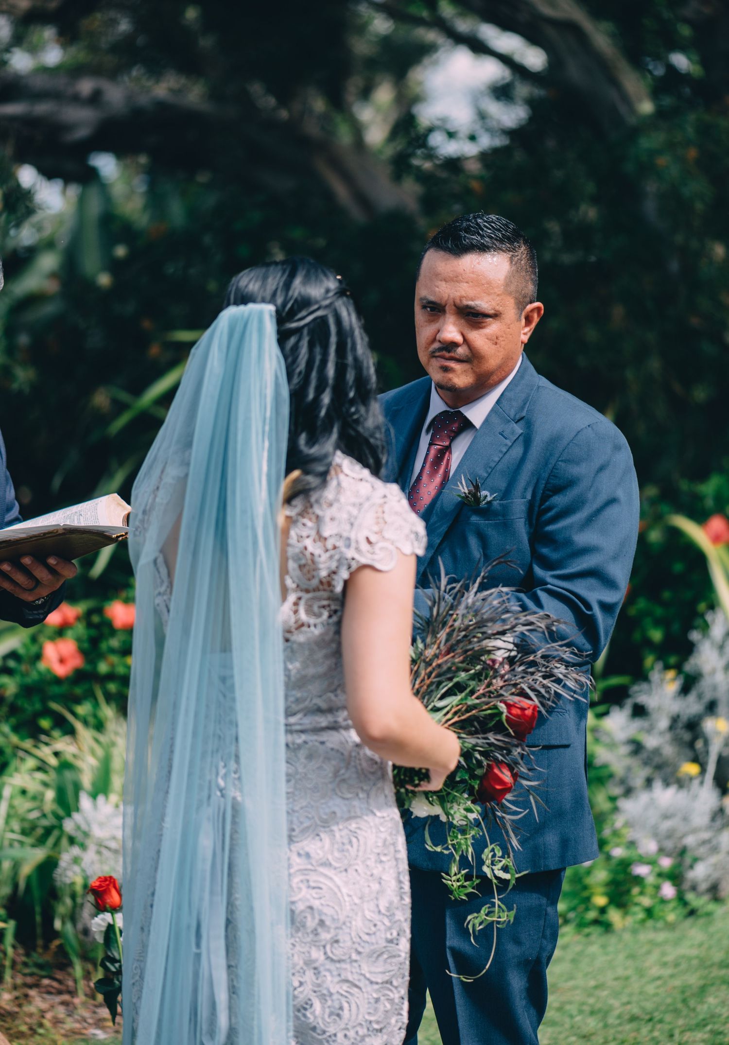 Intimate moment during wedding ceremony with couple in blue suit and lace dress.