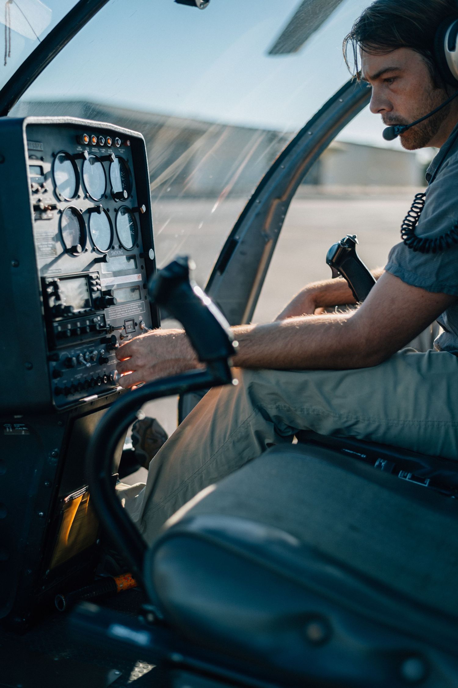 Pilot operating helicopter controls in cockpit with instrument panel visible.