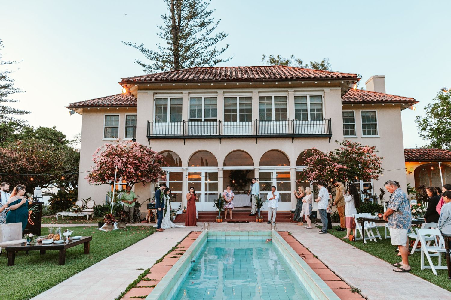 Spanish colonial style venue with white arches and red tile roof overlooking pool and manicured grounds.