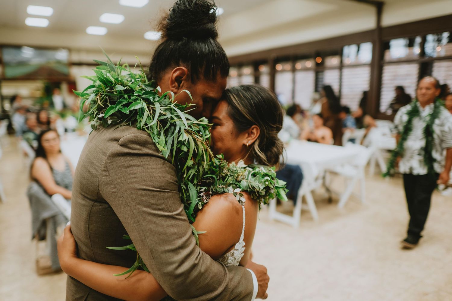 Indoor wedding celebration with guests gathered in a warmly lit venue.