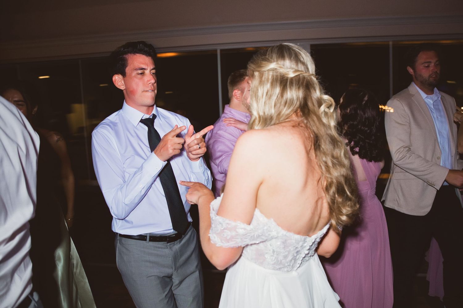 Bride and groom share a joyful dance at their wedding reception, surrounded by guests in elegant attire.