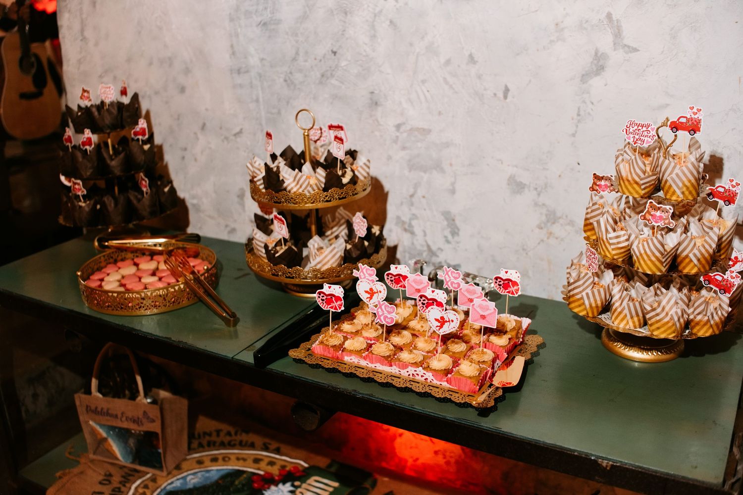Elegant dessert table with tiered cupcake stands, decorated petit fours, and assorted sweets at a festive event.