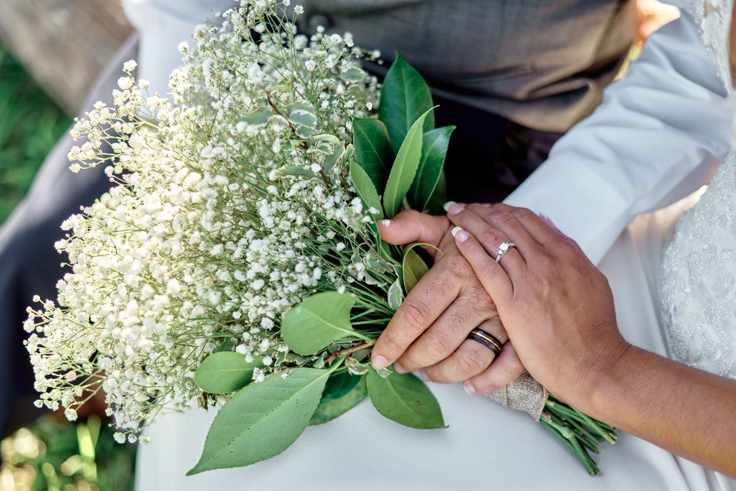 Close-up of delicate baby's breath bouquet and wedding rings against white fabric.