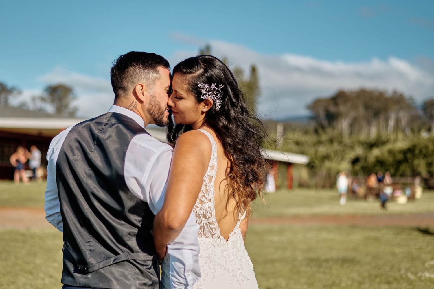 Intimate outdoor portrait of newlyweds embracing against natural landscape.