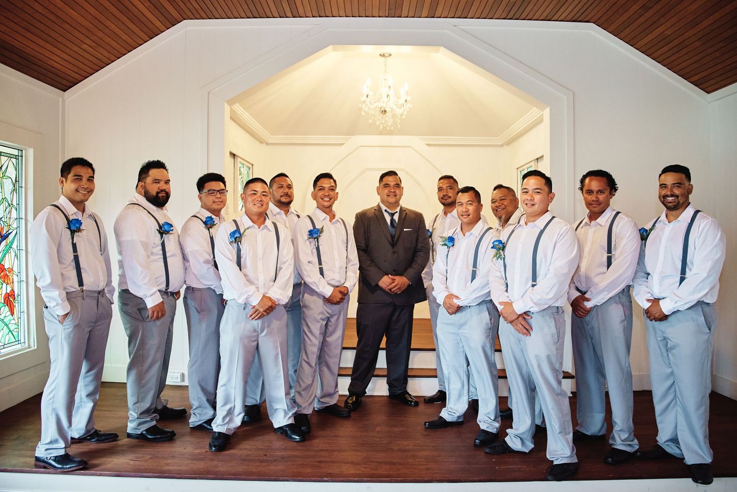 Groomsmen in light gray suits line up for formal wedding photos.