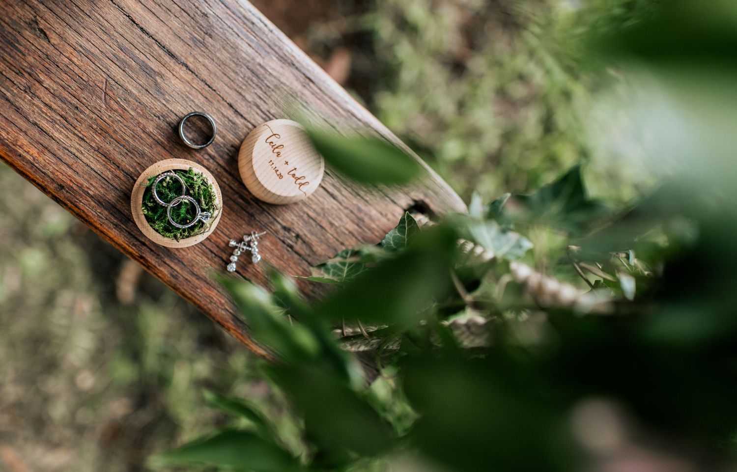 Wedding rings and delicate details displayed on rustic wooden surfaces with natural lighting.