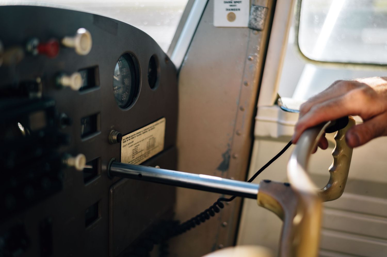Close-up of a hand adjusting controls on an aircraft instrument panel.