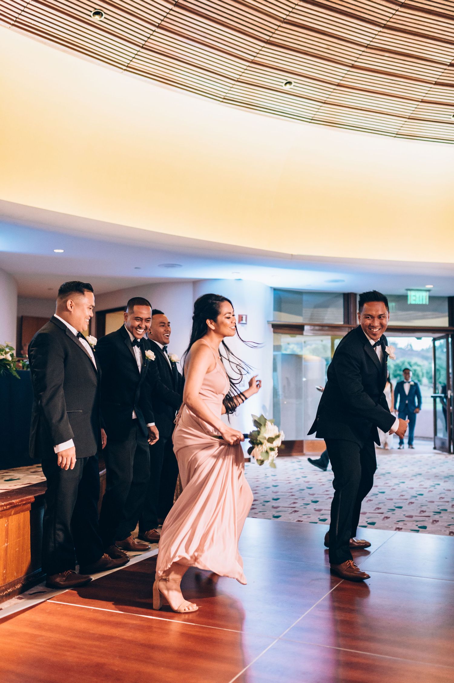 Wedding party members performing choreographed dance routine in reception hall.