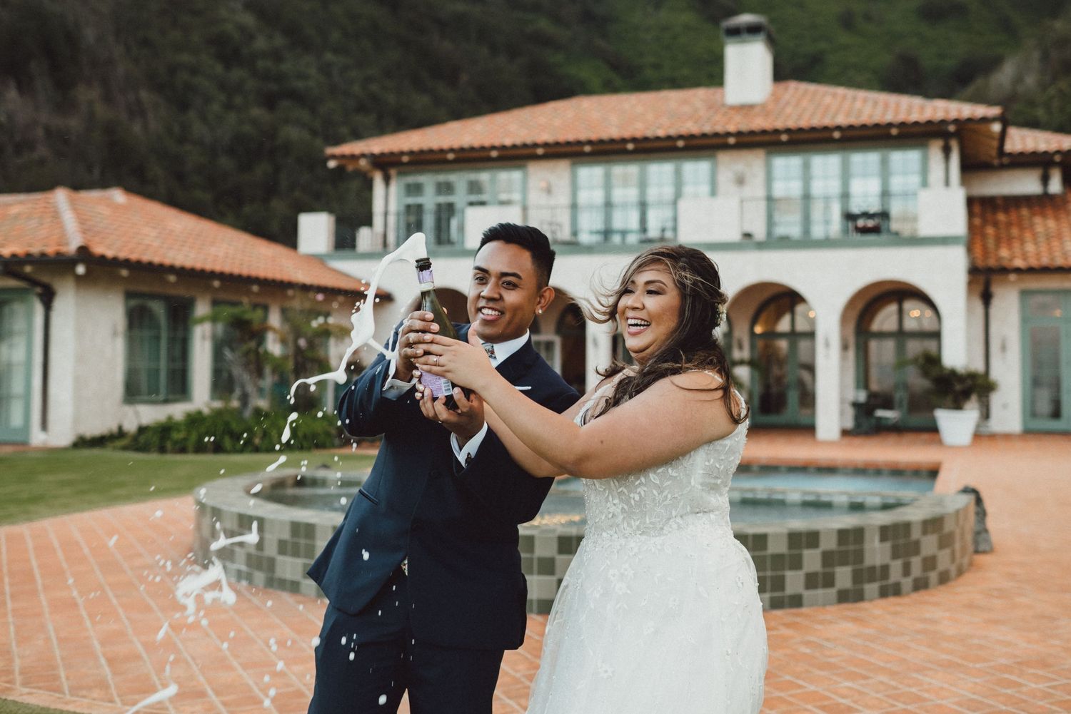 A couple celebrates their wedding day with laughter at a Mediterranean-style venue.