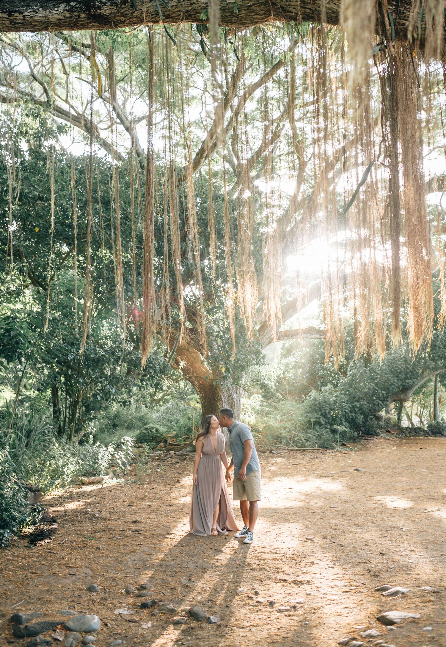 A couple enjoys a romantic moment on a tree-lined dirt path.