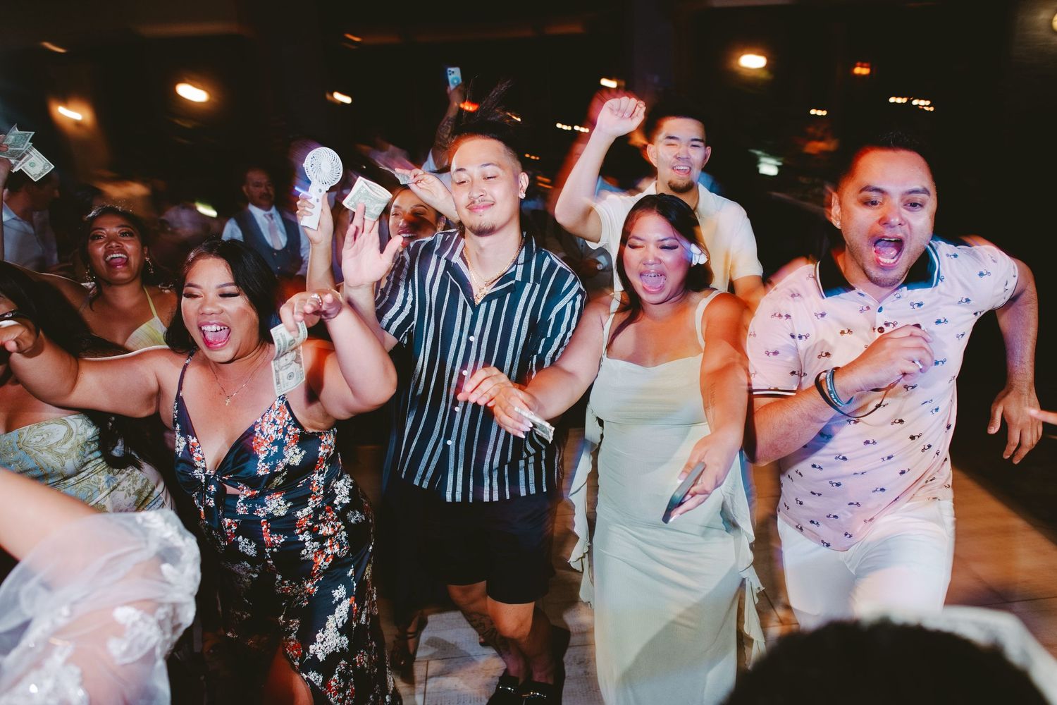 Guests dancing and celebrating joyfully at a lively wedding reception party indoors.