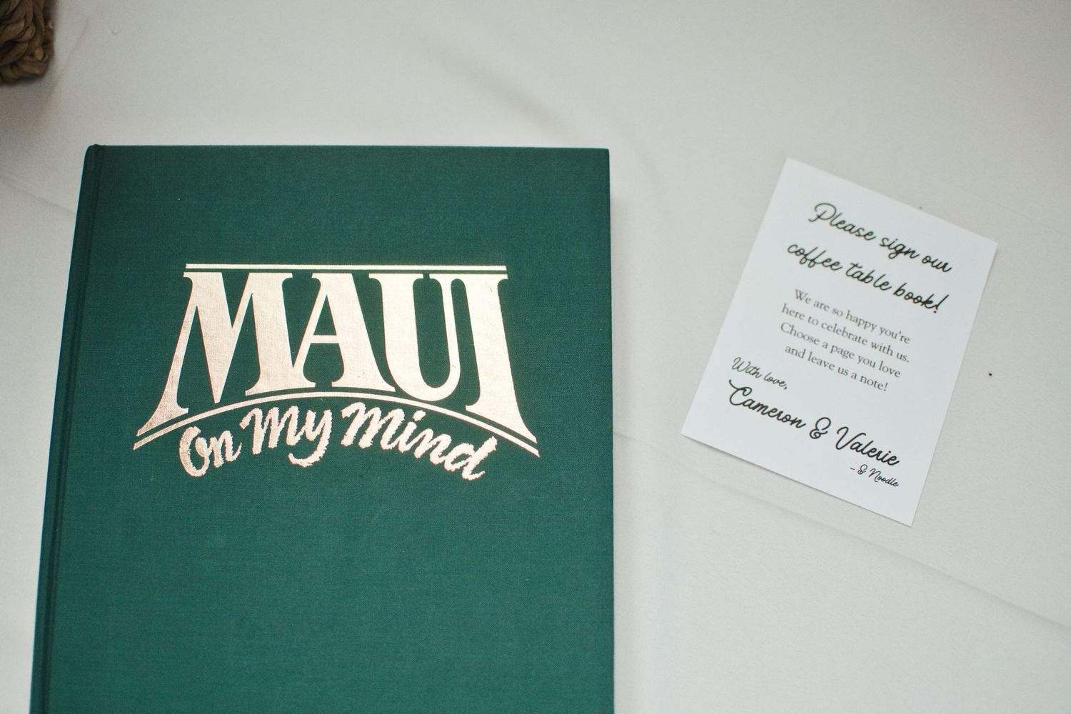 Maui On My Mind green hardcover book displayed next to a wedding table card at a reception.