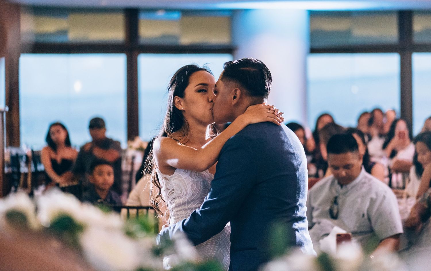 Newlyweds share an intimate dance moment surrounded by guests at their reception.