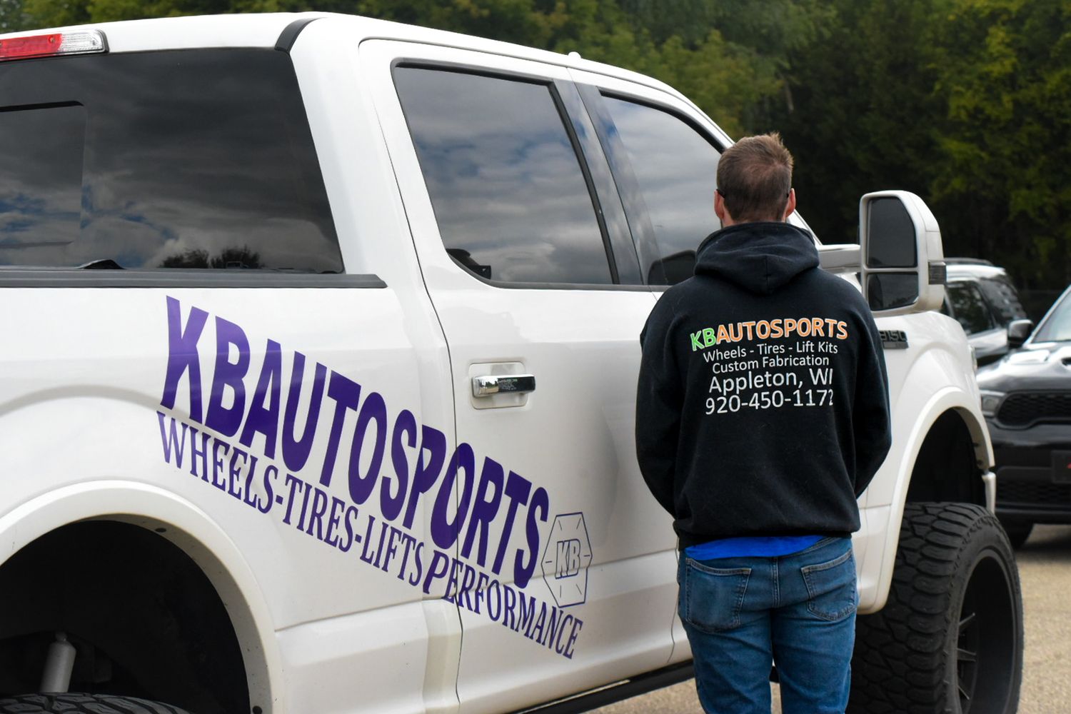 White Ford F150 truck with KBAutoSports logo with employee next to vehicle for a branding session.