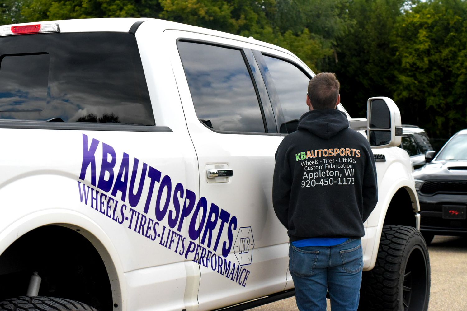 White Ford F150 truck with KBAutoSports logo with employee next to vehicle for a branding session.