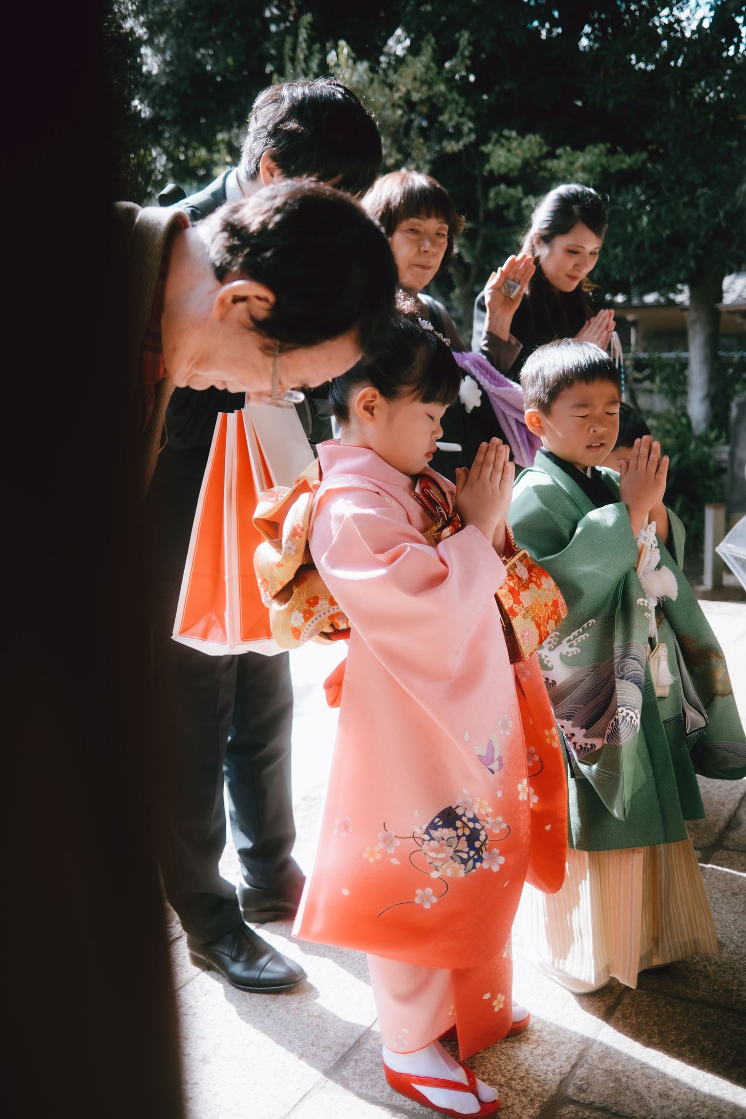 Children in traditional Japanese kimono pray with hands together at a Shichi-Go-San ceremony at a shrine in Chiba.